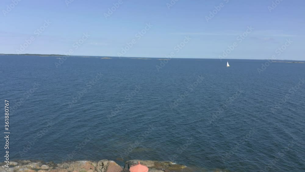 Aerial view flying backward over open sea, remote island with washed lighthouse Aerial view flying backward over open sea, remote island with washed lighthouse