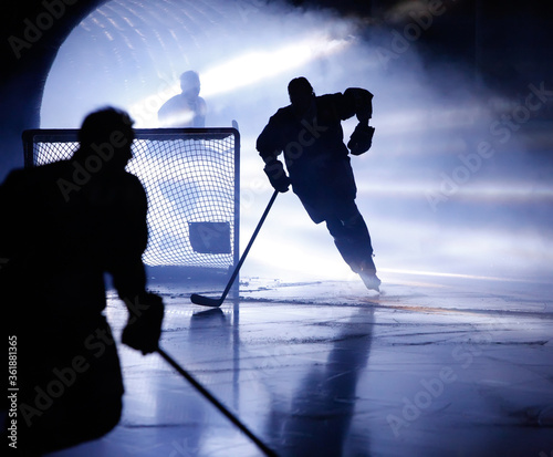 A silhouette of an ice hockey player skating out from a player entrance with smoke and light rays pouring out it.
