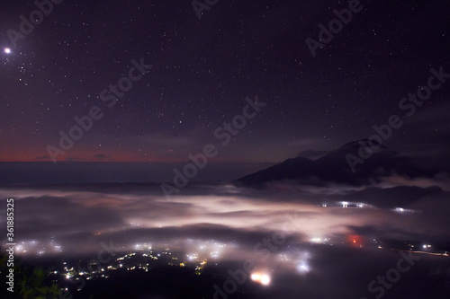  Bali indonesian island from the top of Batur mountain at the night time with night star sky and city lights at the bottom
