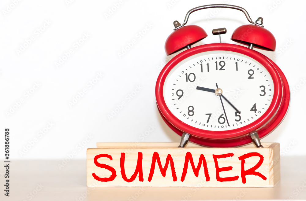 an alarm clock and a chalkboard with the text summer time on the sand of a beach an alarm clock and a chalkboard with the text summer time on the sand of a beach