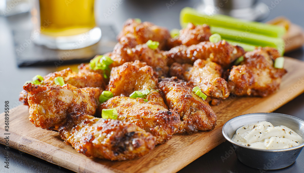 pile of bbq garlic bone-in chicken wings on wooden board pile of bbq garlic bone-in chicken wings on wooden board