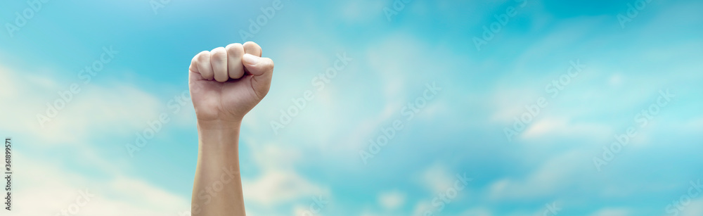 Hand of man with clenched fist on sky background Hand of man with clenched fist on sky background
