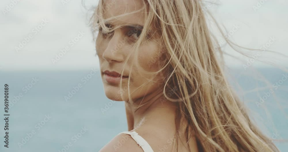 Portrait of a beautiful woman with wind blowing through her hair in slow motion, confident young beauty