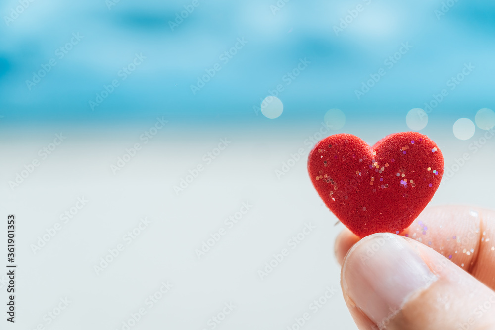 Hand hold little heart meaning feel love with summer beach with blue sky.