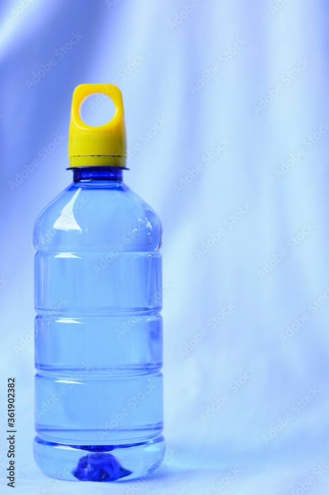 A blue plastic bottle water with yellow bottle cap isolated on blue sky background.