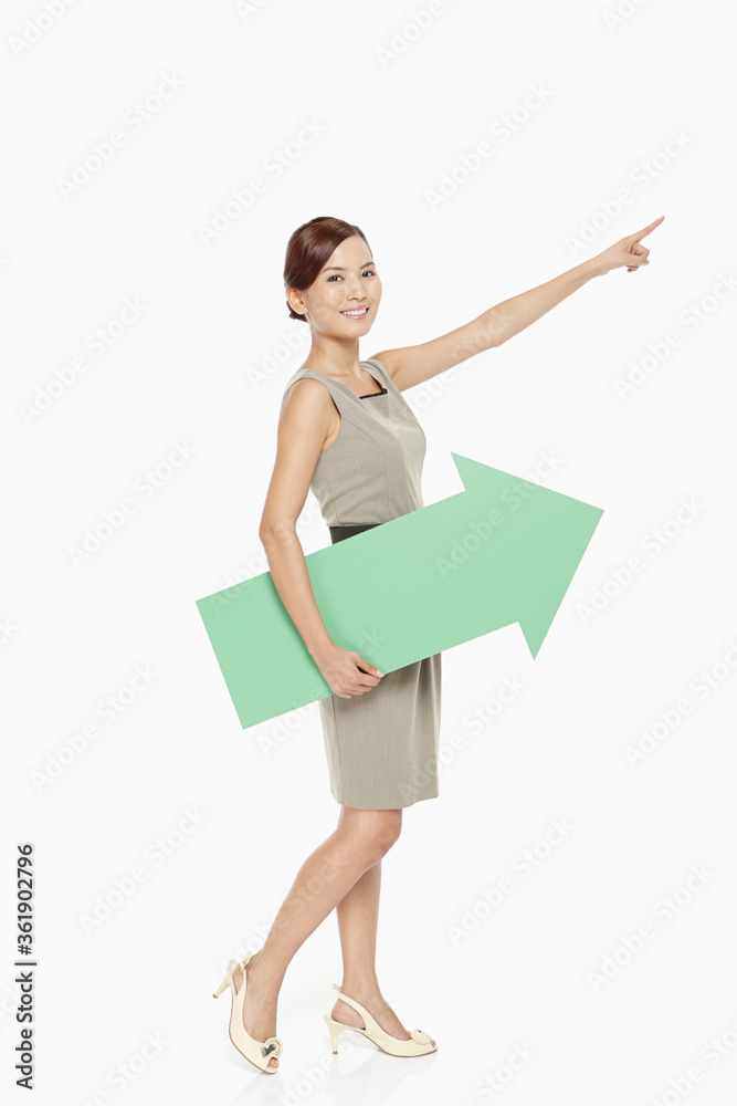 Businesswoman holding a green arrow, facing left Businesswoman holding a green arrow, facing left