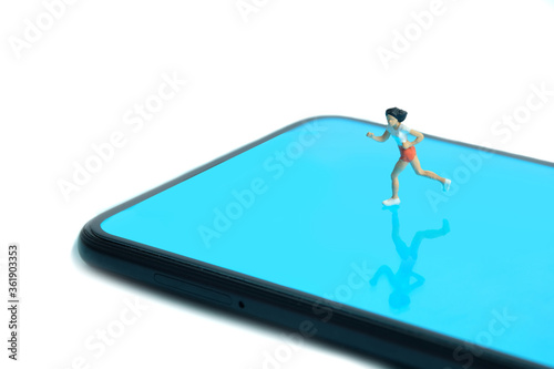 Running and jogging tracking app concept. A women running above smartphone. Miniature people figure photography. © miniartkur