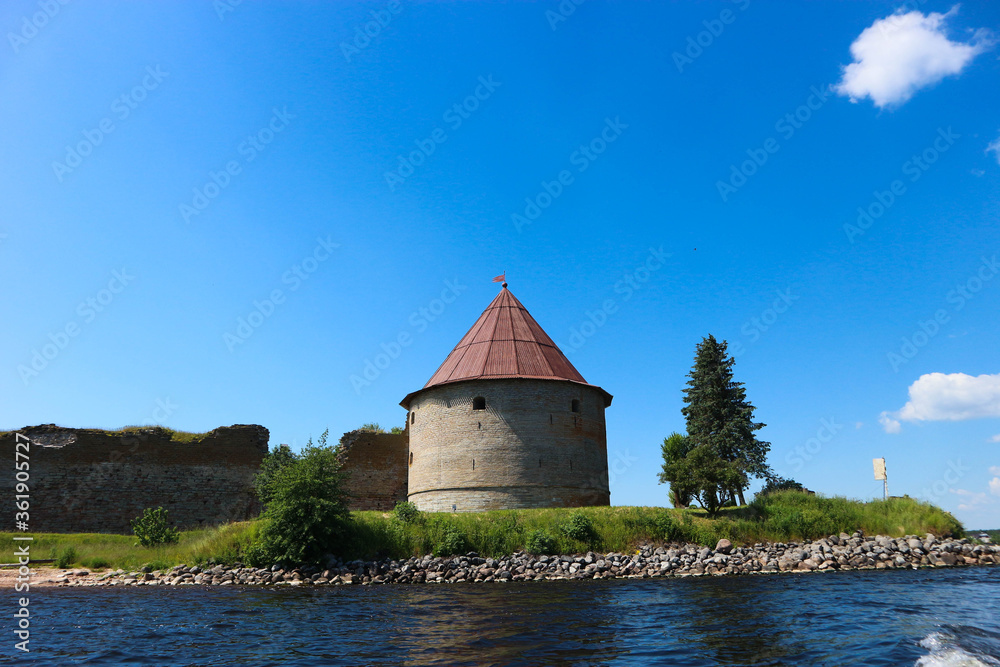 Fototapeta premium Corner tower of medieval Shlisselburg (Oreshek) fortress on the island in the Ladoga lake in Russia against blue sky