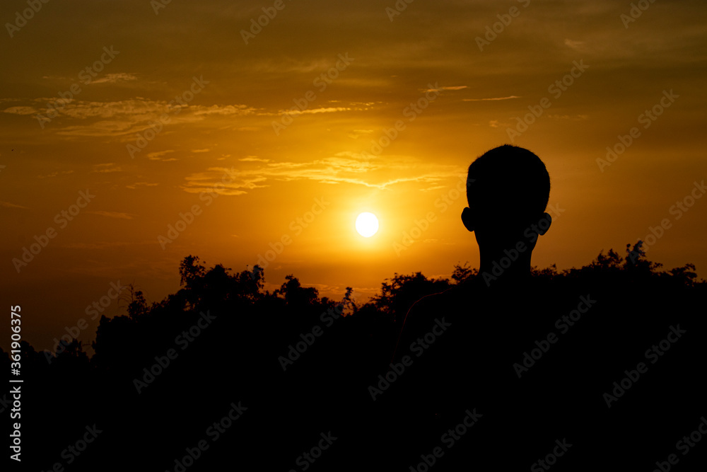 Young boy stands alone on sunset time.Silhouette of boy, concept of lonely, sad, alone and scared.Man Stand under the sky.enjoying sunset moment outdoors.