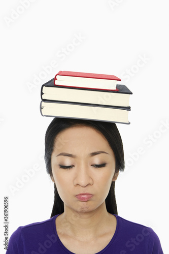 Woman with a stack of books on her head, sulking