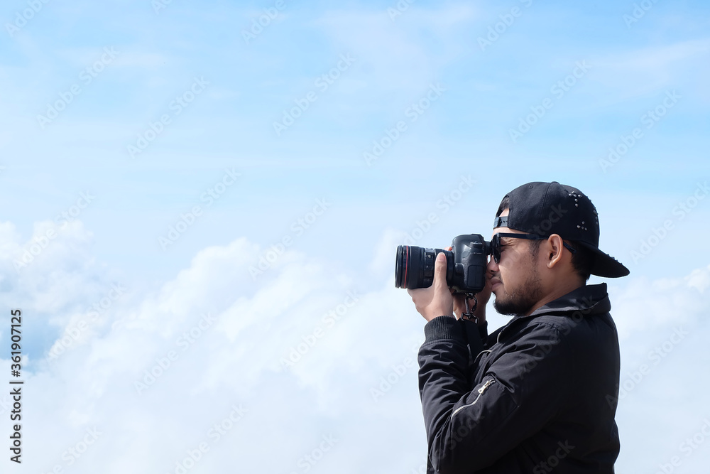 Travelers man hold a camera, take pictures beautiful landscape cloudy background.