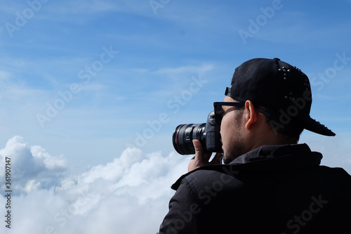 Travelers man hold a camera, take pictures beautiful landscape cloudy background.