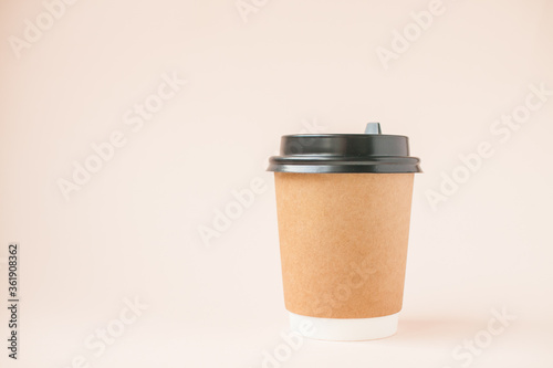 Disposable paper cups with a plastic lid on a light pink background.