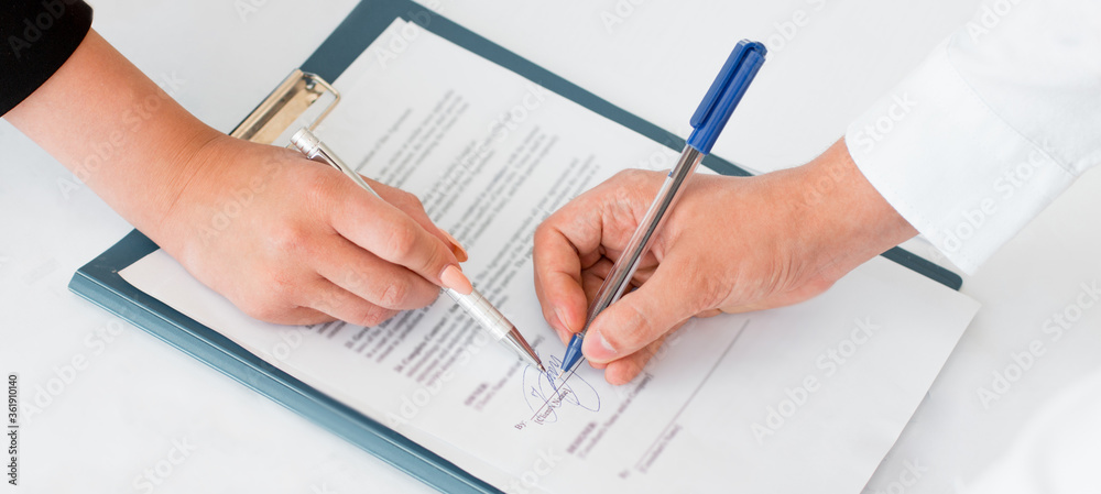 Close-up of hands signing contract agreement Close-up of hands signing contract agreement