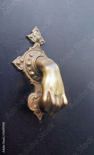 Fotografie, Obraz bronze hand knocker or caller of a door over a black background -  mystical symb