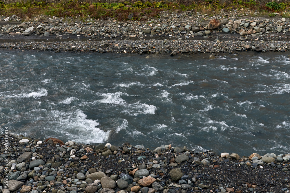 Obraz premium nature and travel concept - river water flow and stones