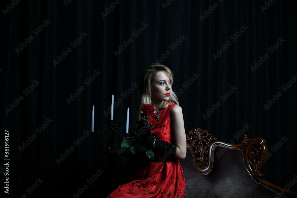 young and beautiful girl in a red dress in a romantic style with a candelabrum