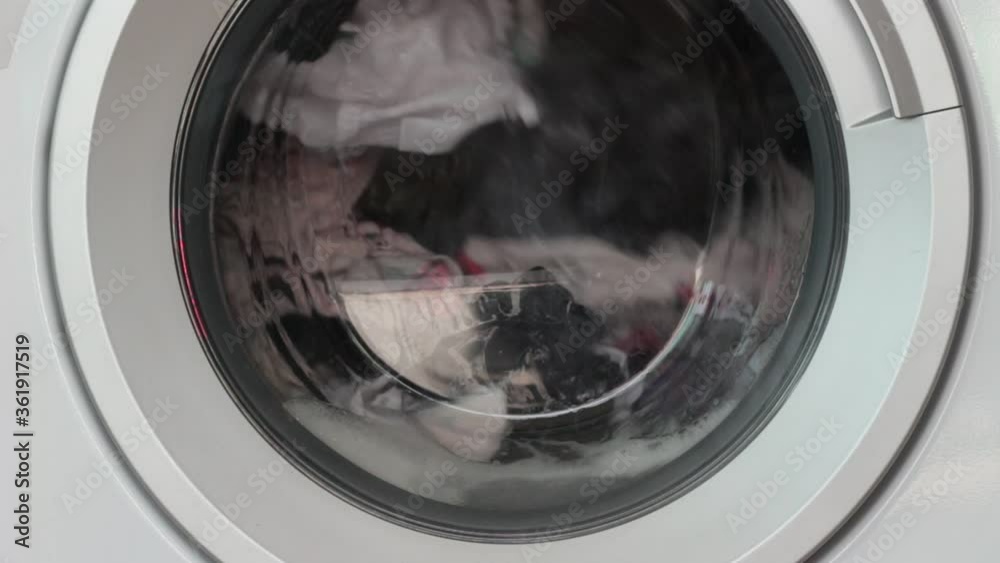 washing machine working with rotating garments inside, process of cleaning cloth with washing machine, laundry concept washing machine working with rotating garments inside, process of cleaning cloth with washing machine, laundry concept