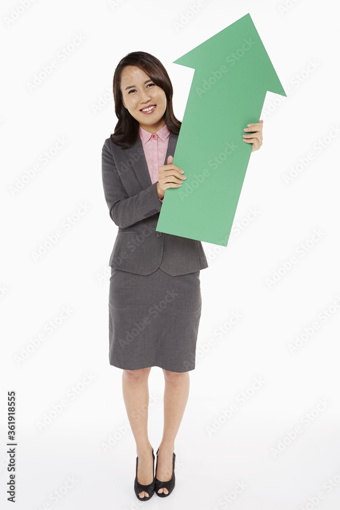 Businesswoman holding an arrow, pointing upwards Businesswoman holding an arrow, pointing upwards