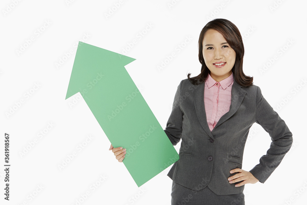 Businesswoman holding an arrow, pointing upwards Businesswoman holding an arrow, pointing upwards
