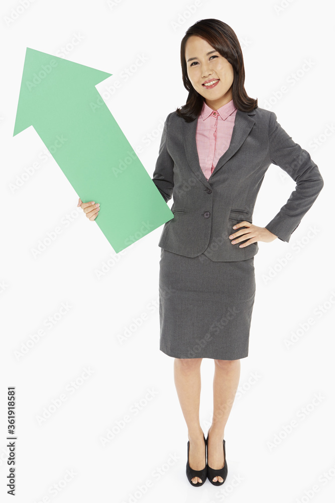 Businesswoman holding an arrow, pointing upwards Businesswoman holding an arrow, pointing upwards