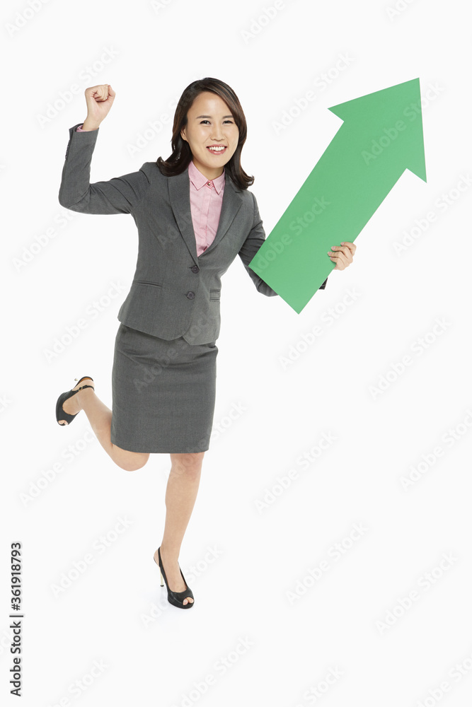 Businesswoman holding an arrow, pointing upwards Businesswoman holding an arrow, pointing upwards