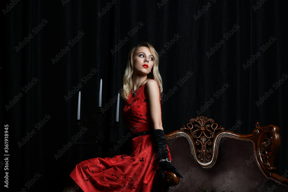 young and beautiful girl in a red dress and a candelabrum with candles
