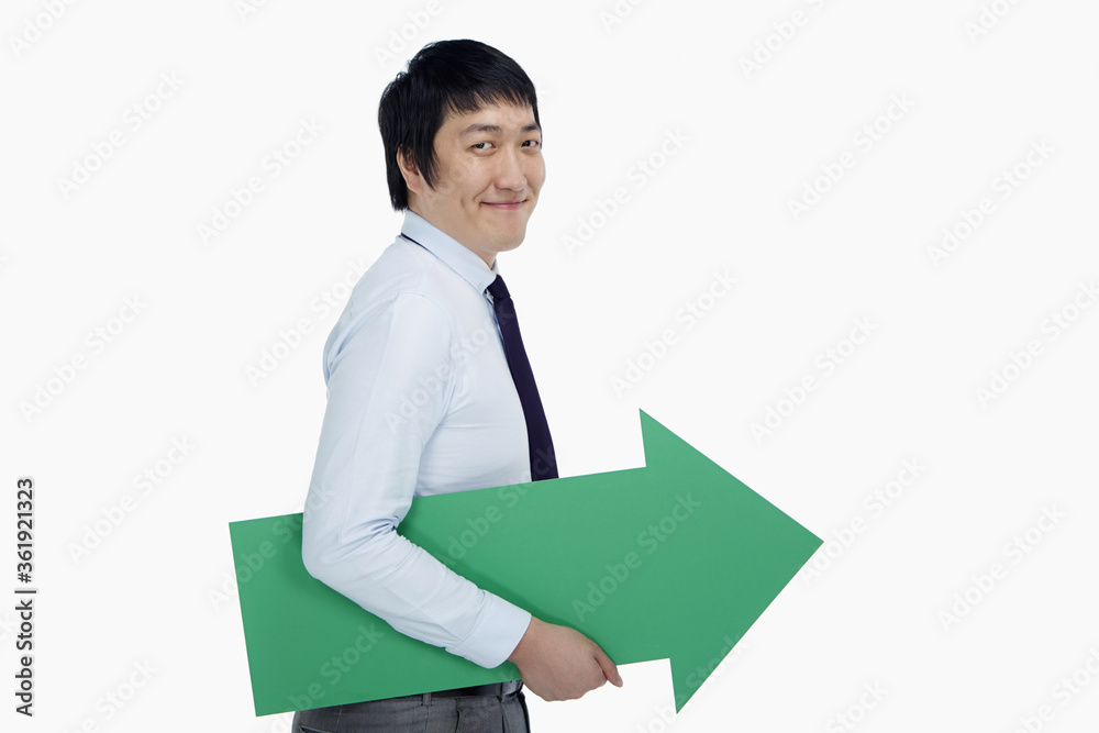 Businessman holding an arrow, pointing to the left Businessman holding an arrow, pointing to the left