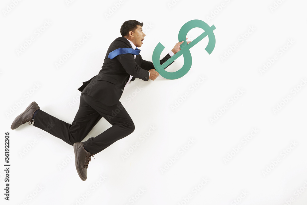 Businessman hanging on to a dollar sign Businessman hanging on to a dollar sign