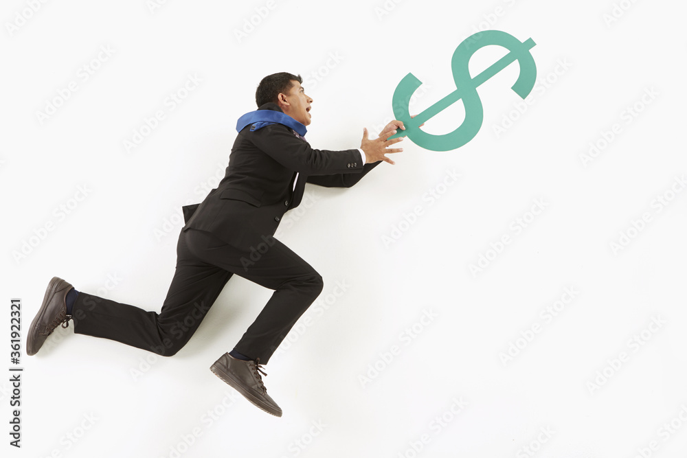 Businessman hanging on to a dollar sign Businessman hanging on to a dollar sign