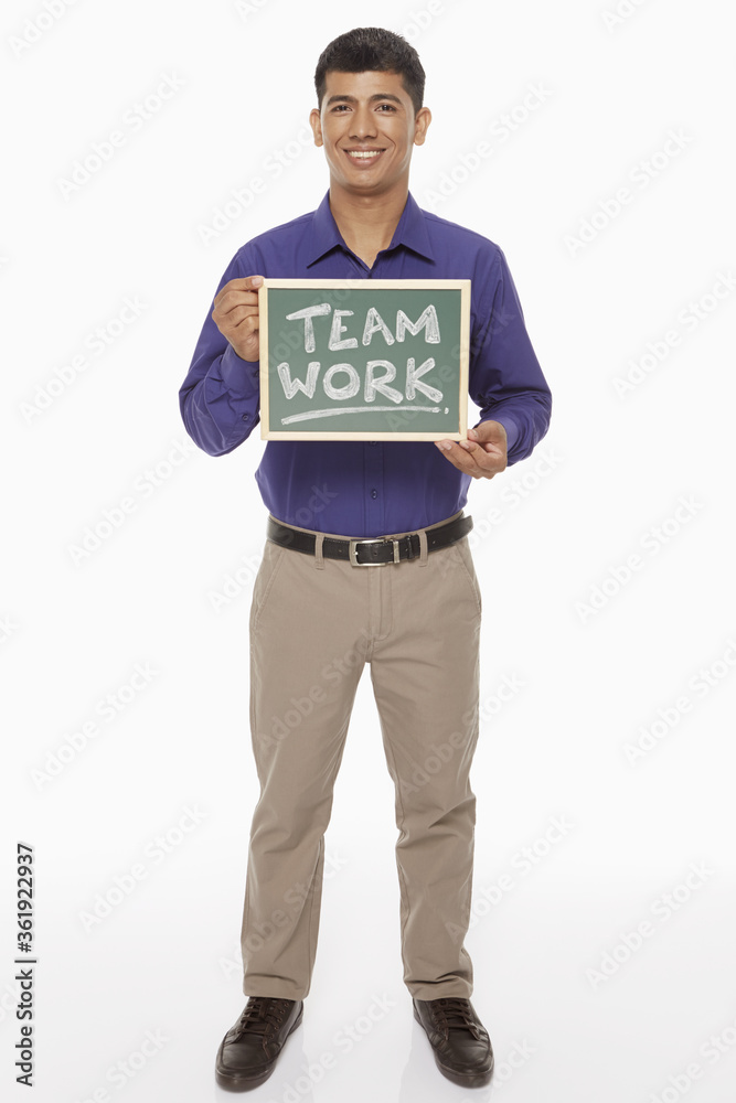 Businessman holding up a blackboard with 'Team work' written on it Businessman holding up a blackboard with 'Team work' written on it