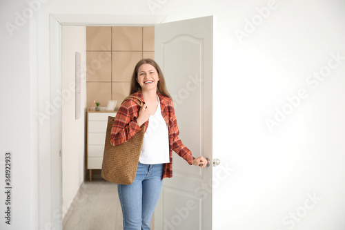 Happy woman opening door at...