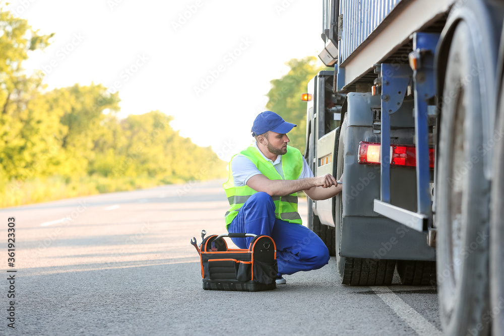 Male driver fixing big truck outdoors