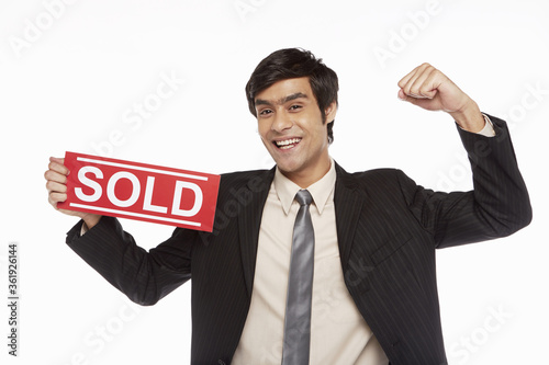 Businessman holding up a 'Sold' sign, cheering