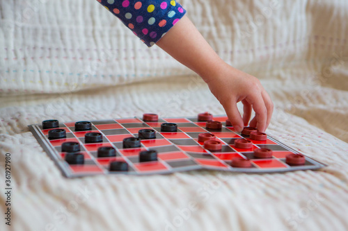 checkers close-up. black and red map. the hand holds the chip. games for development of logic