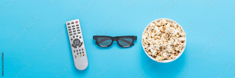 Bowl with popcorn, Imax glasses, remote control for TV on a blue Bowl with popcorn, Imax glasses, remote control for TV on a blue