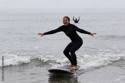 Photography Young multiracial African American lady with amazing smile, freckles & frizzy hair & an Asian Japanese Surf Instructor having a surf lesson together in Chiba, Japan They are wearing black wetsuits