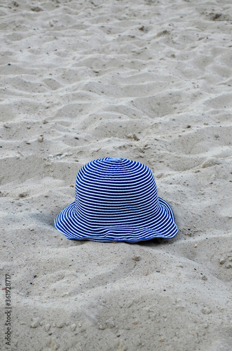 A woman's hat is lying on the seashore. Panama on the background of sand. Near. Concept: vacation, travel, summer.