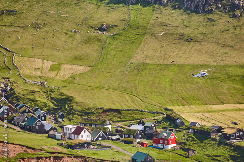 Helicopter flying over mykines village in Faroe. Denmark photo