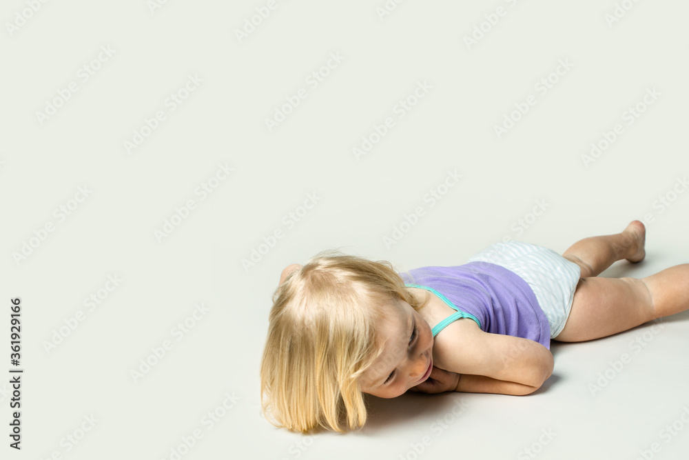 Beautiful little baby smiling while lying on her stomach on a white background Beautiful little baby smiling while lying on her stomach on a white background