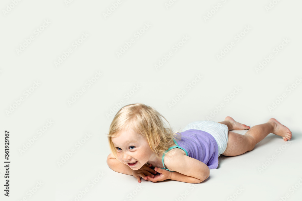 Beautiful little baby smiling while lying on her stomach on a white background