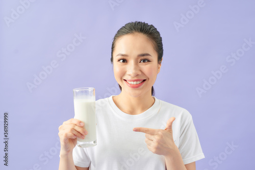 Young beautiful woman drinking a glass of milk over purple isolated background with surprise face pointing finger to herself