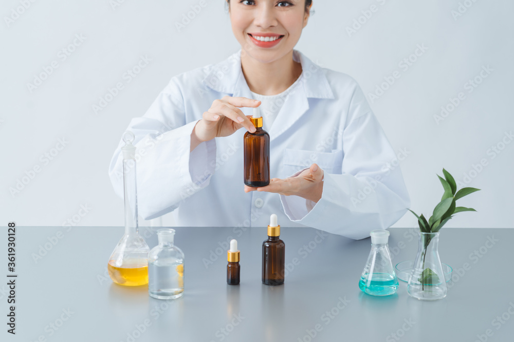 Female dermatologist holding bottle of skin care product at table, closeup Female dermatologist holding bottle of skin care product at table, closeup