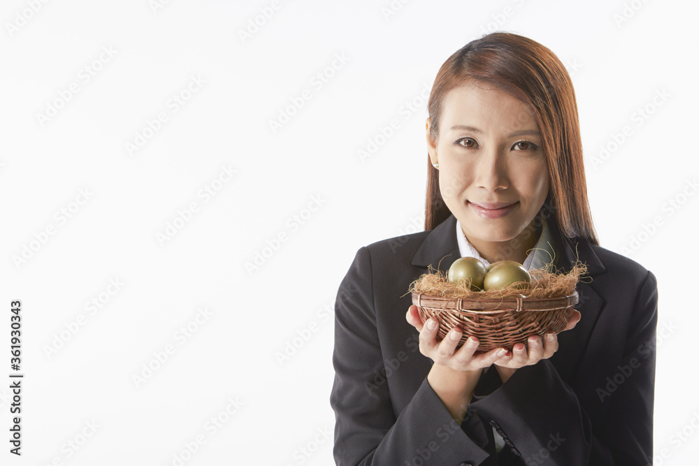 Businesswoman carrying a nest filled with gold eggs Businesswoman carrying a nest filled with gold eggs