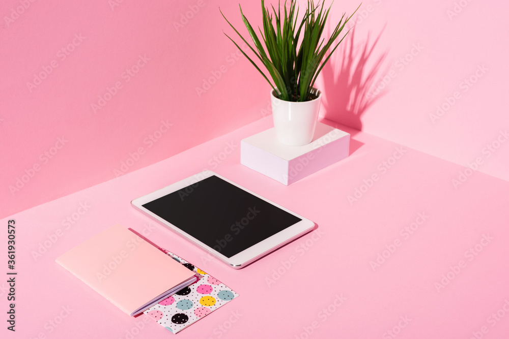 digital tablet with blank screen, notebooks, plant on pink background digital tablet with blank screen, notebooks, plant on pink background