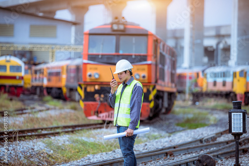 Portrait engineer under inspection and checking construction process railway switch and checking work on railroad station .Engineer wearing safety uniform and safety helmet in work.