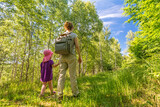 Mother and daughter hiking through the beautiful green forest in summer
