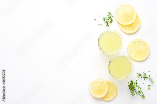 Lemon slices and glasses of limoncello on white background. Top View Bright Summer Alcohol Drink Concept photo