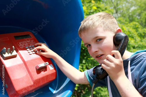 Foto Boy dials number on street fixed telephone