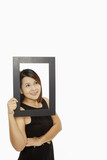 Cheerful woman holding up a black picture frame